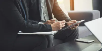 Werkgever en nieuwe medewerker bespreken documenten op een tablet tijdens de proeftijd