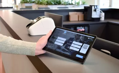 Een bezoeker die zich registreert op een tablet voor bezoekersbeheer bij de receptie van een gebouw