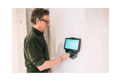Employé pointant avec un badge sur une pointeuse mural