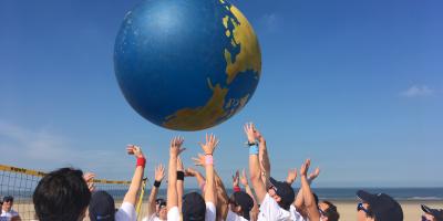Team op strand met bal in vorm van wereldbol